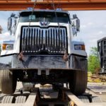 a photo showing a made in Canada new JT Fabrication roll off truck body being loaded on a flatbed